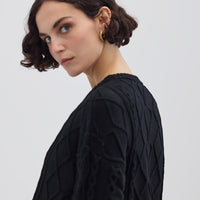Side profile of model in Black Cable Knit Sweater – warm and effortlessly chic knitwear