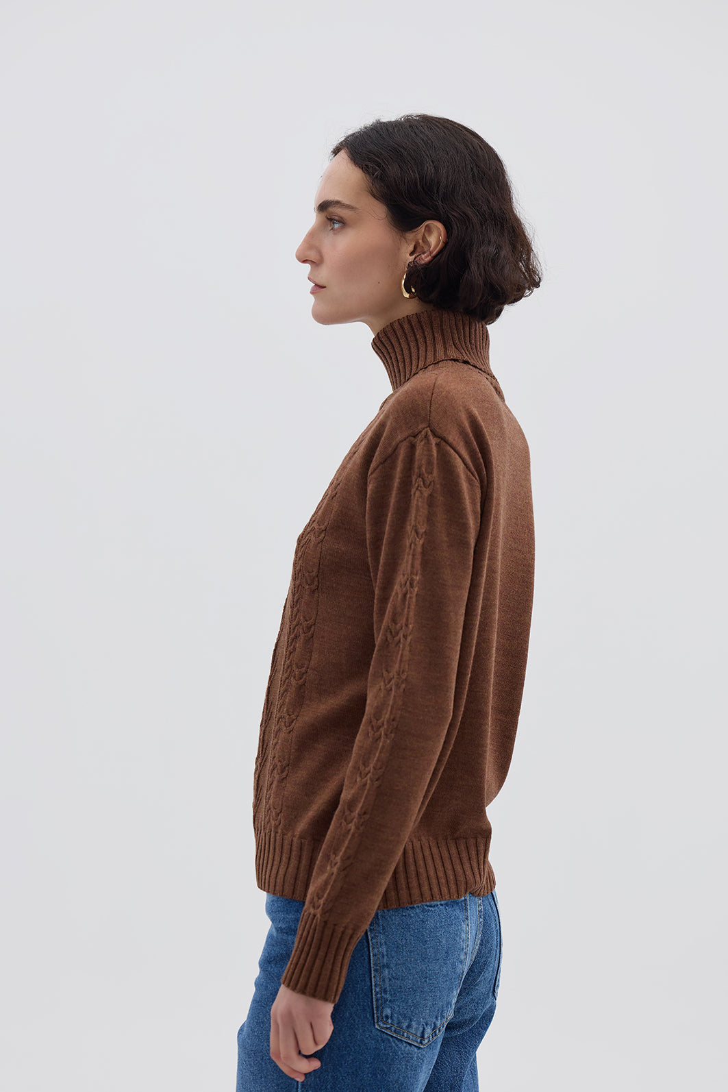 Side profile of model in Walnut Cable Knit Sweater – roll neck and ribbed cuffs for classic winter style