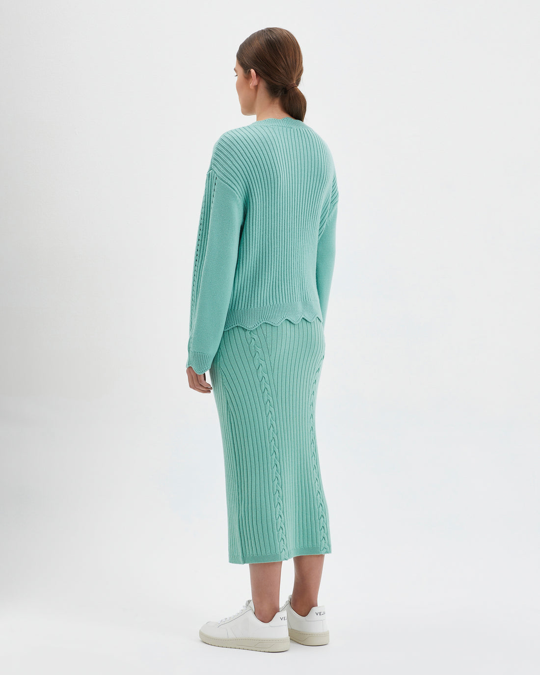 Feminine wool sweater in sage featuring delicate scalloped details on neckline, waist, and cuffs.