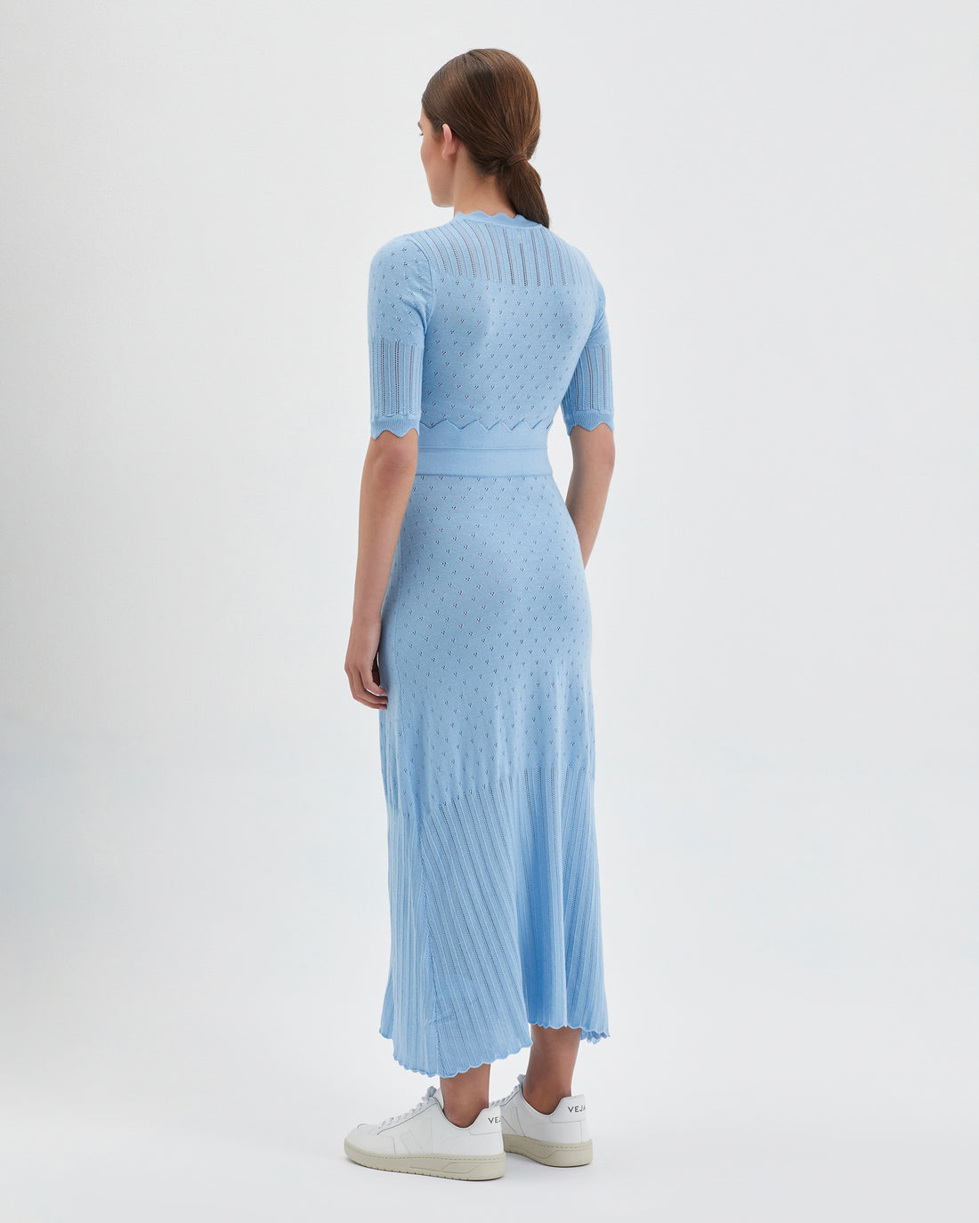 The dress features a fitted bodice with short sleeves, intricate pointelle details.