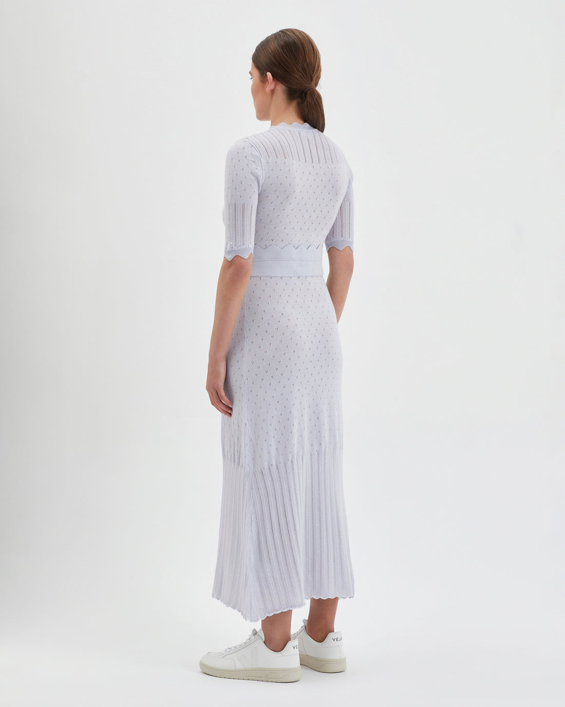 The dress features a fitted bodice with short sleeves, intricate pointelle details.